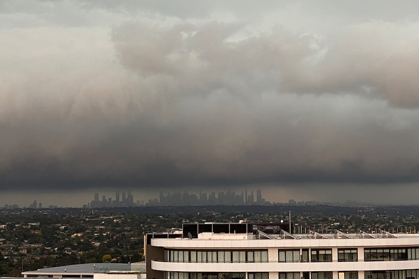 A building in the foreground with a line of very dark stormclouds blanketing Melbourne's skyline.