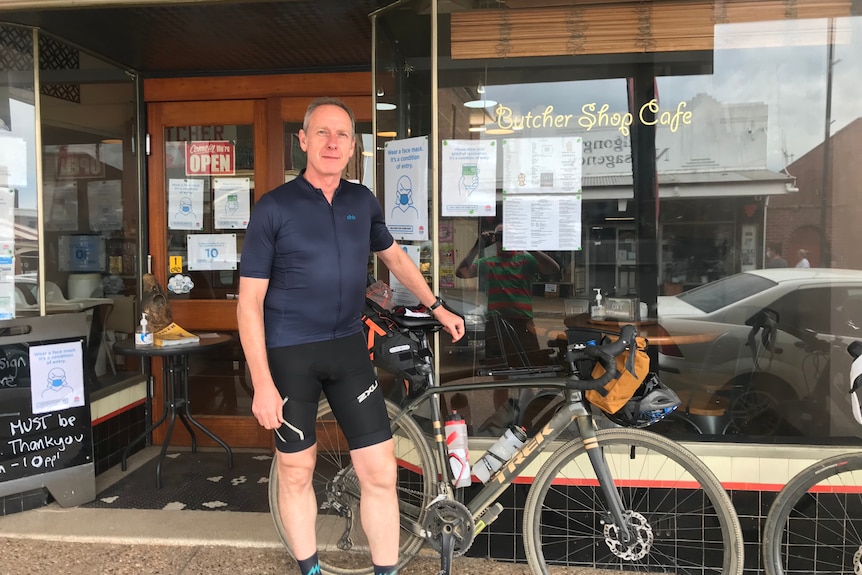 David Mark stands next to his bike outside a cafe.