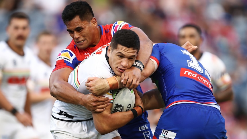 Penrith Panthers' Dallin Watene-Zelezniak looks to squirm out of a wrap tackle from two Newcastle Knights players