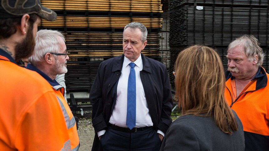 Bill Shorten, with his hands in his pockets, listens to men in high-vis jumpers. Justine Keay has her back to the camera
