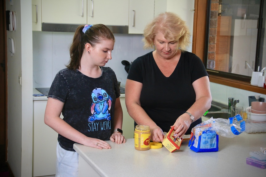 A middle aged woman in the kitchen with her teenage daughter
