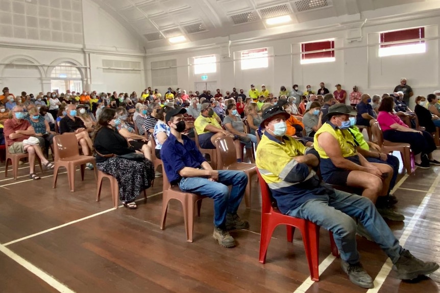 A room full of masked people attended a community meeting.