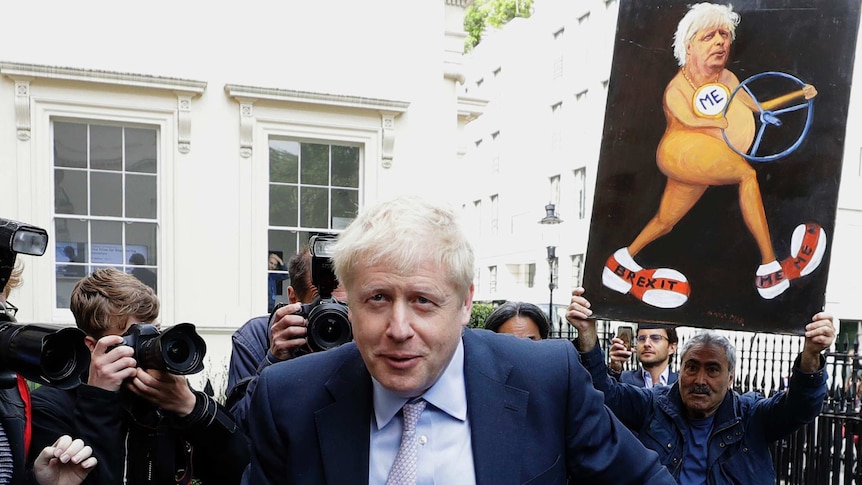 Boris Johnson walks in front of a media scrum in front of a white Georgian building in London.