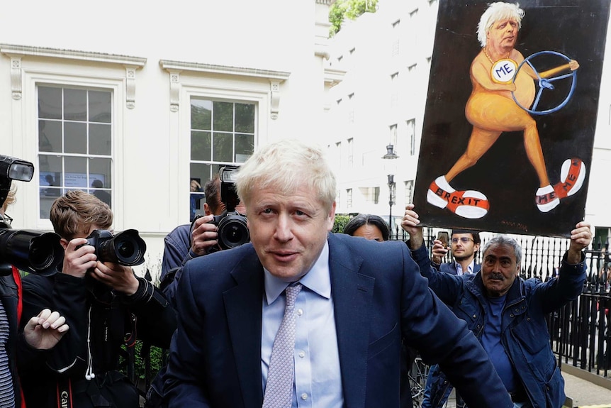 Boris Johnson walks in front of a media scrum in front of a white Georgian building in London.