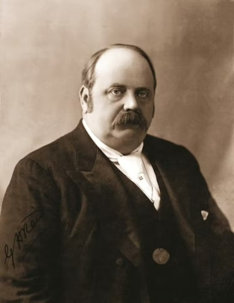 A black and white portrait of a heavy set man with a walrus moustache