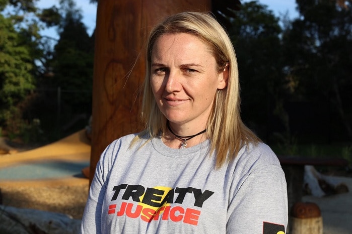 Fiona Newson is dressed in a T-shirt reading "Treaty = Justice" as she stands in front of a park.