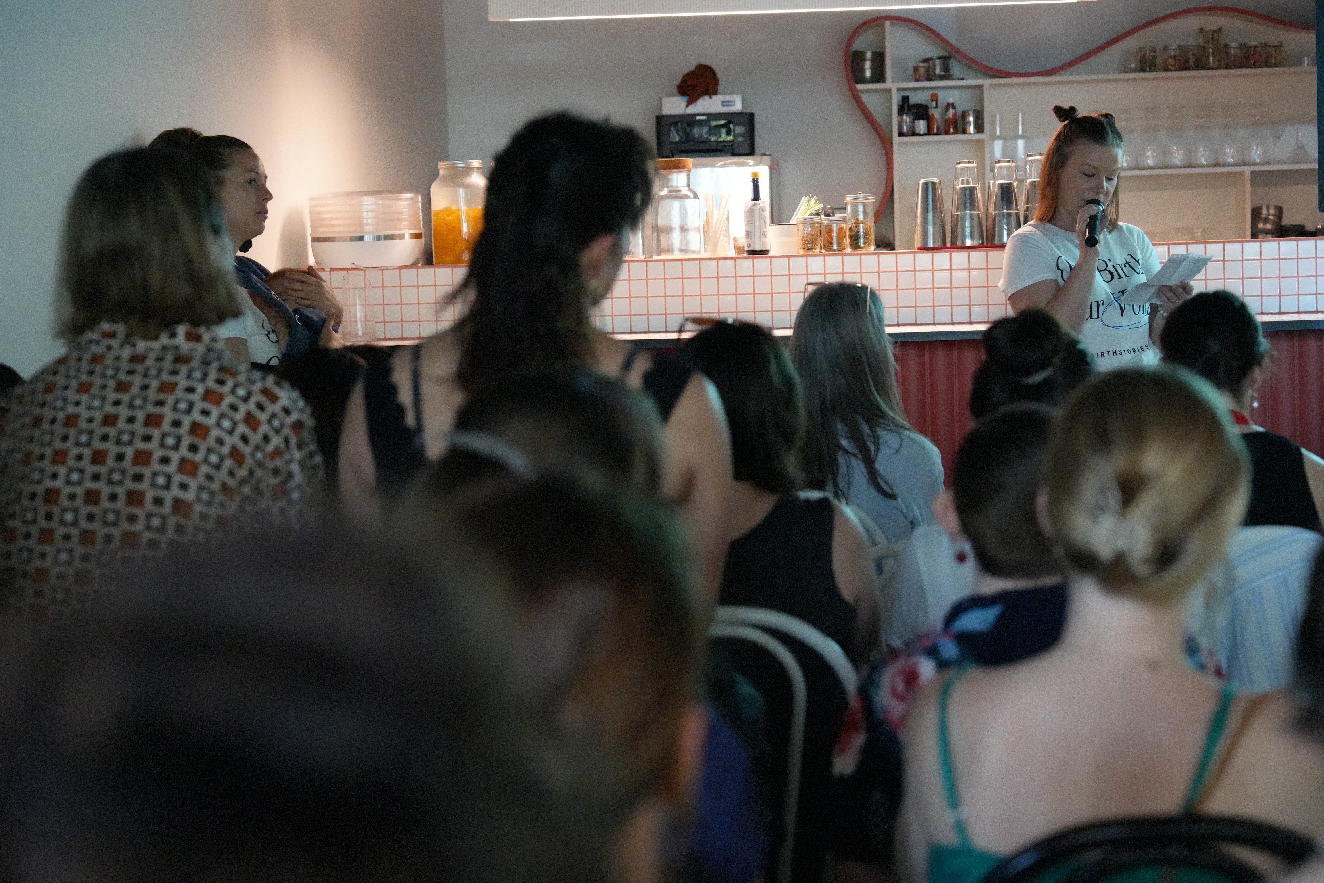 Uma mulher falando na frente de uma multidão. 