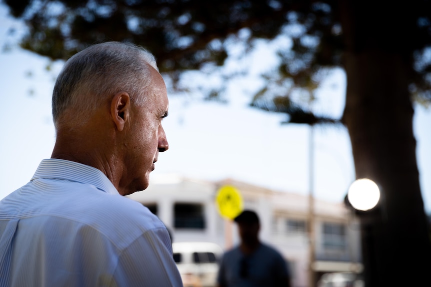 A man in a white shirt photographed from behind