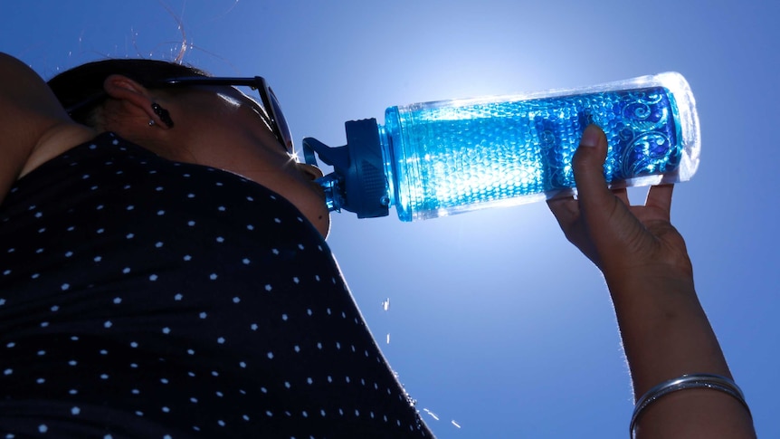 Woman drinks from water bottle.