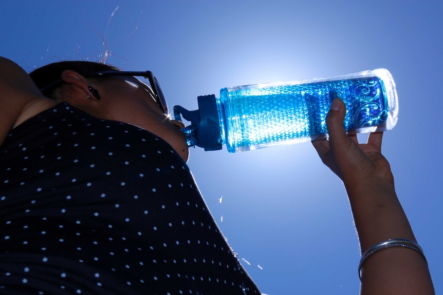 Woman drinks from water bottle.