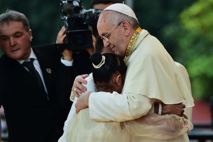 Pope Francis embraces three children in Manila