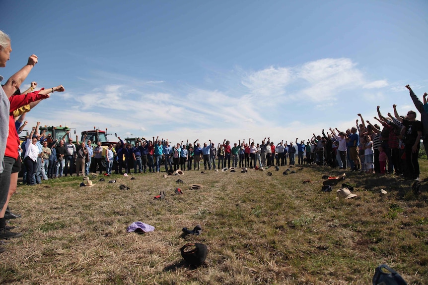 a group of people in a circle formation raising their hands