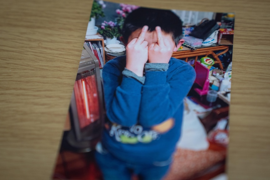 A photo of a boy holding up his middle finger on both hands.