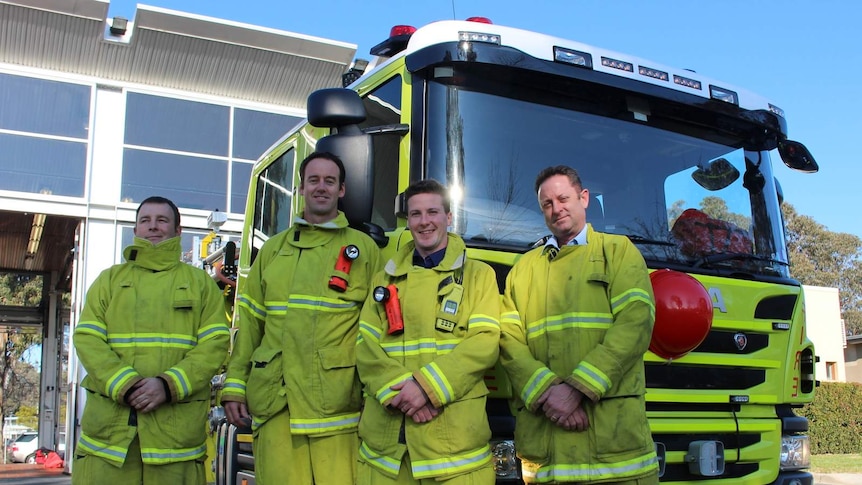 Four fire fighters stand in front of their fire engine outside Ainslie Fire station