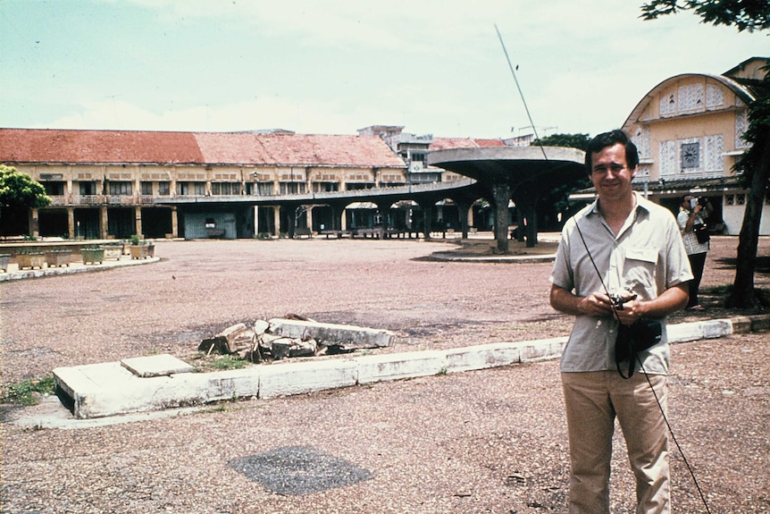 A faded photo from the 70s shows a man standing in front of an abandoned market.