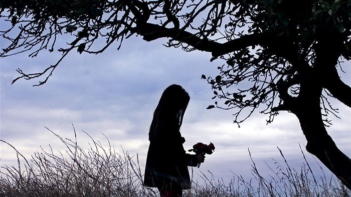 A girl with a bouquet of flowers in silhouette.