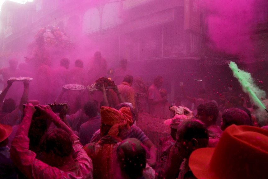 Indian devotees proceed with offerings to Lord Krishna chariot procession amidst veils of colored powder