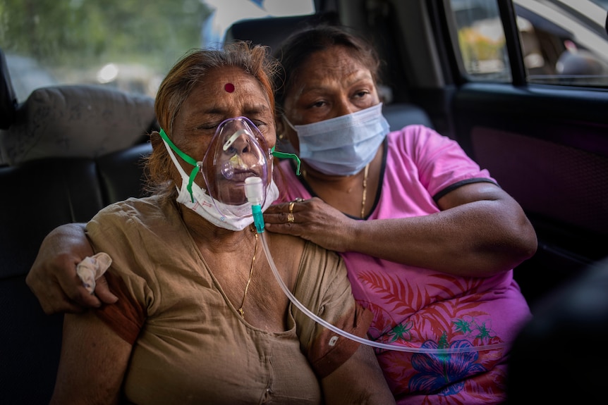 A COVID-19 patient is given oxygen in the back of a car