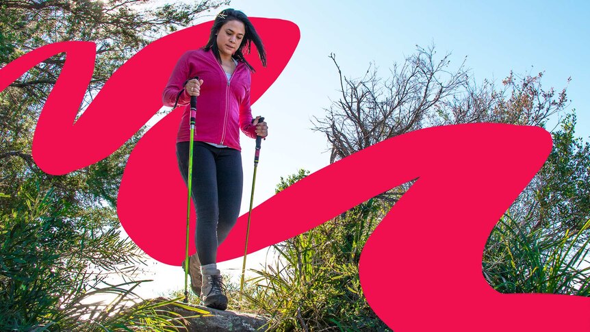 A woman with hiking sticks traverses the hiking path.
