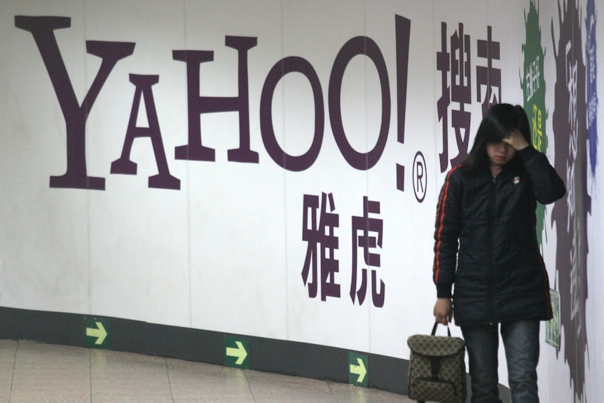 A woman walks past a Yahoo billboard in a subway.