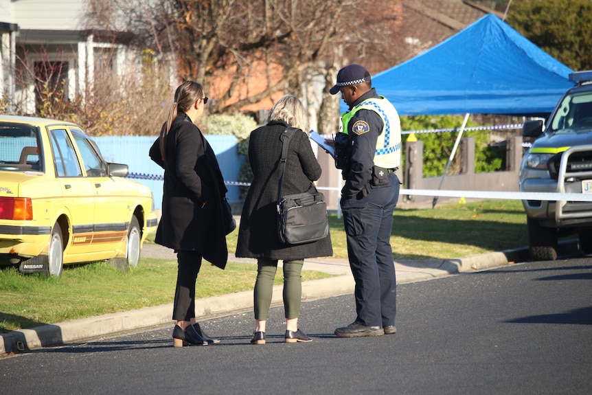 Two women talk to a police officer