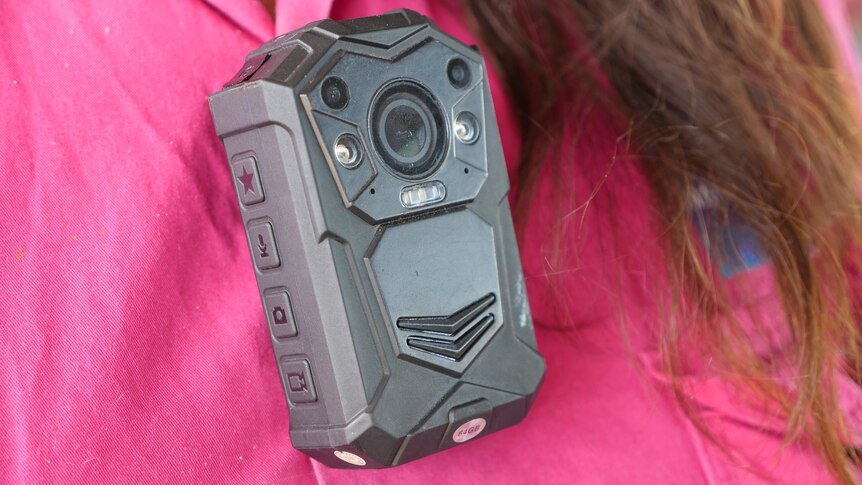 A body-worn camera pinned to a brightly coloured shirt.