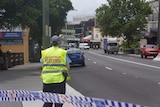 A police officer stands in a street in Wollongong after a fatal shooting
