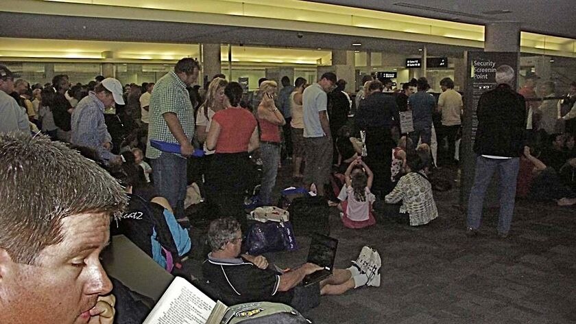 Passengers stand around at Brisbane Airport on the night after a false security alarm