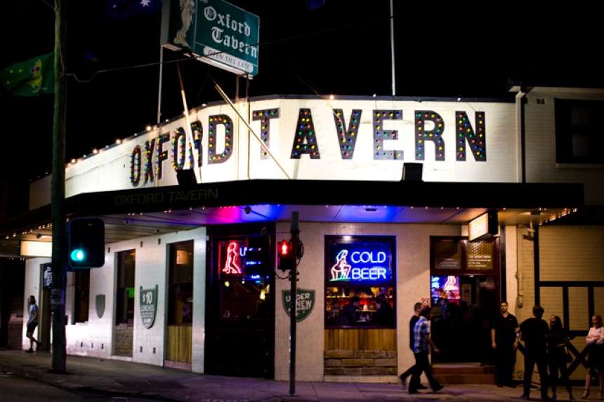 Nighttime exterior of a pub with two people walking past. 