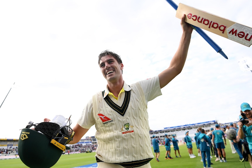 Australia batter Pat Cummins holds up a bat and stump after winning an Ashes Test at Edgbaston.