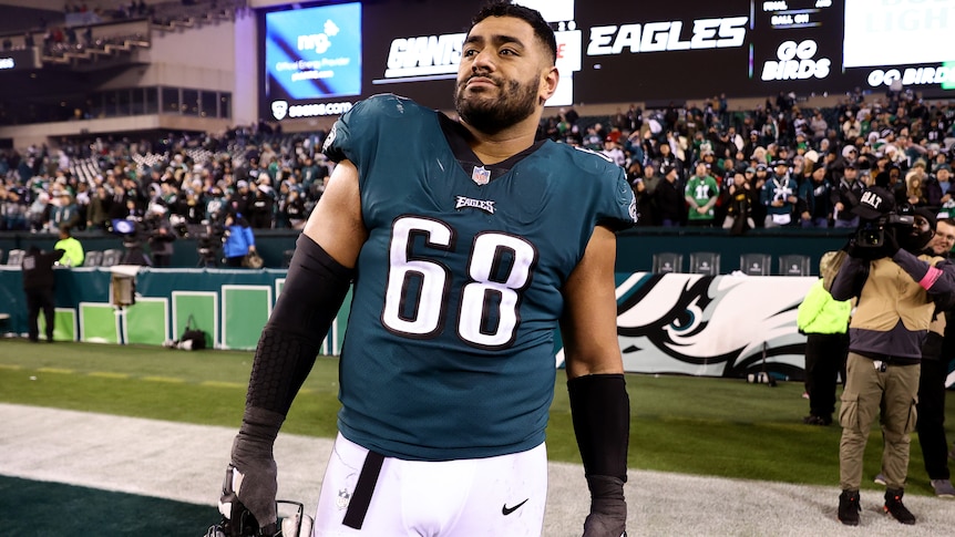 An Australian NFL player stands in his Philadelphia Eagles playing uniform after a match.