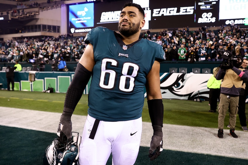 An Australian NFL player stands in his Philadelphia Eagles playing uniform after a match.