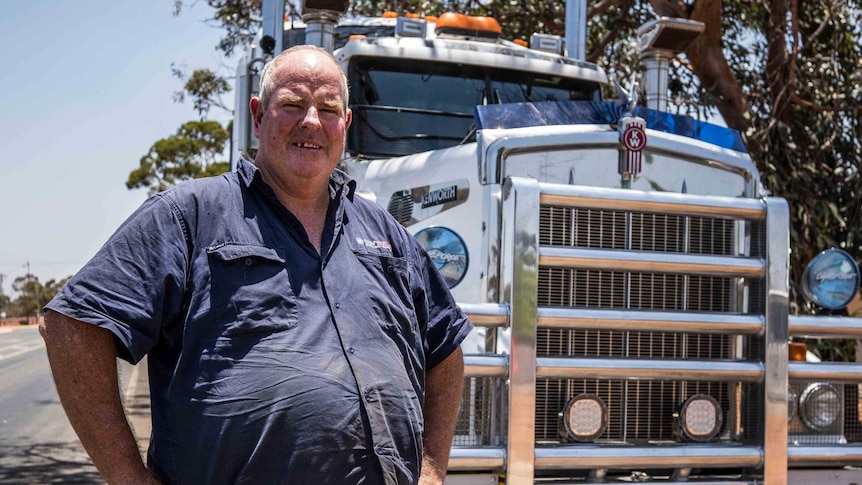 Truck driver standing in front of road train.
