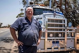 Truck driver standing in front of road train.