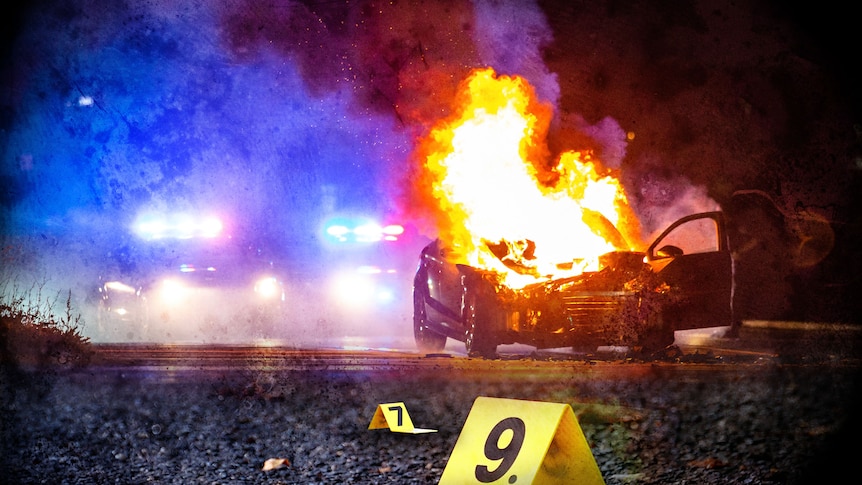 A car on fire with flashing lights seen through the mist of smoke, and numbered evidence markers on the road