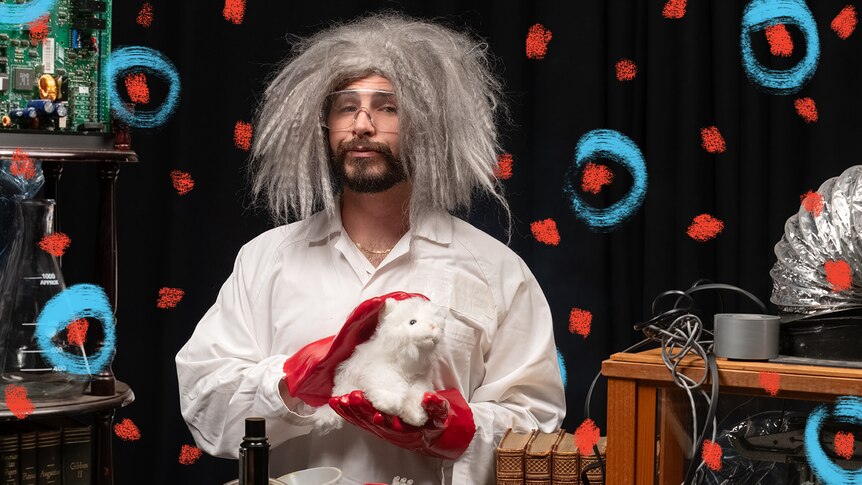 Joe dressed up as a mad scientist holding a cat, sciency equipment around him.