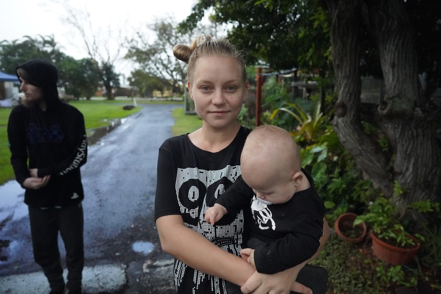 Young woman wearing a black shirt holding a toddler in her arms.