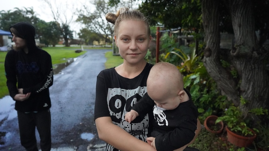 Young woman wearing a black shirt holding a toddler in her arms.