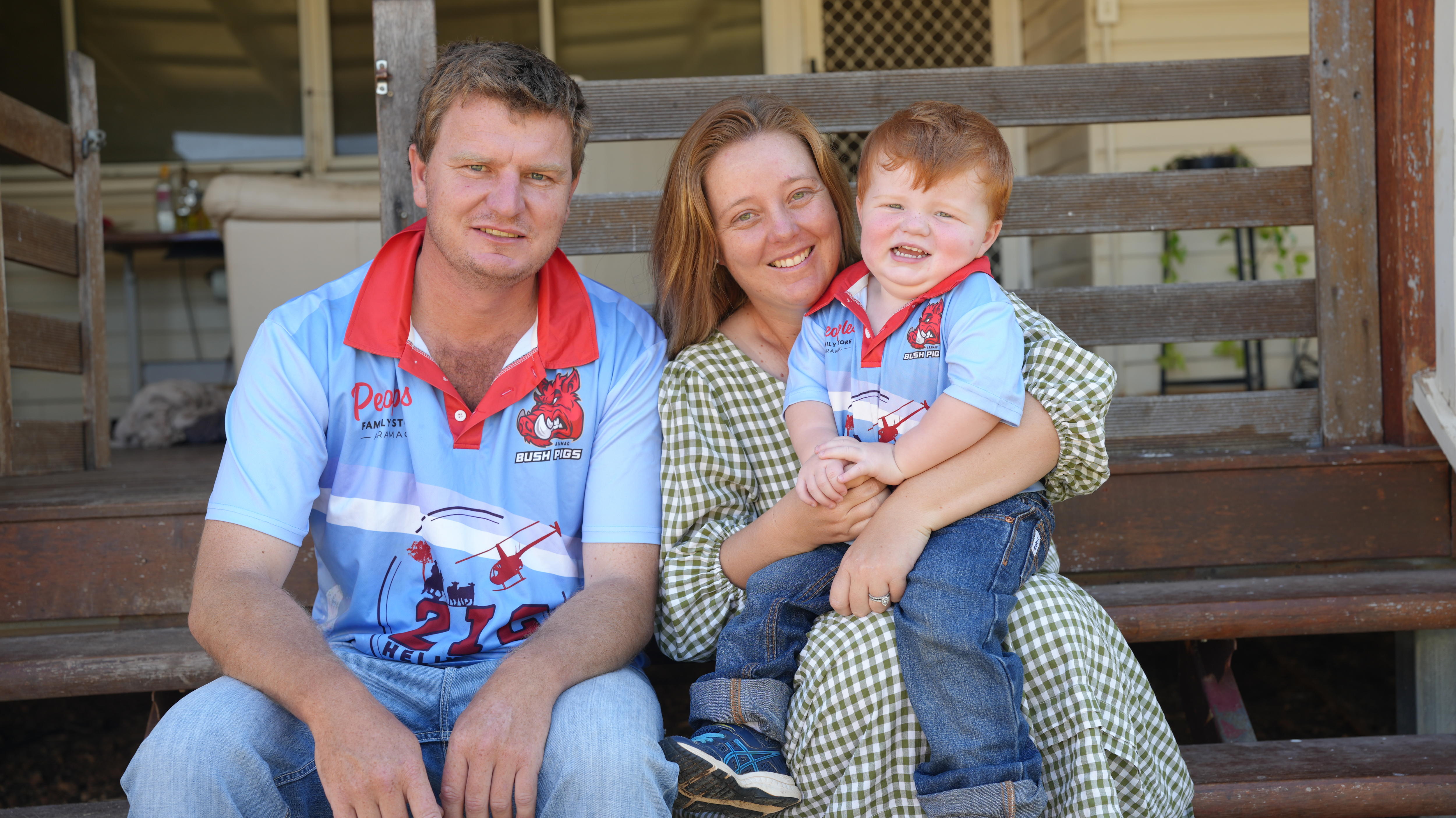 A man, women and child sit together on the back steps of their home