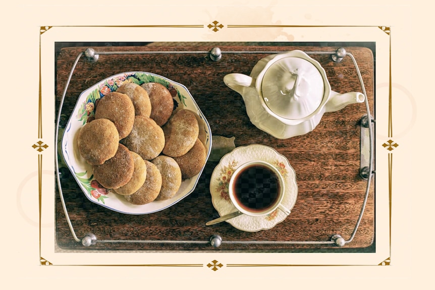 A tray of baked biscuits, a teapot and cup of tea