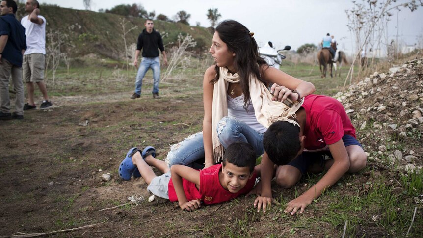 A woman and her children take cover as sirens wail in Tel Aviv, Israel, November 17, 2012.