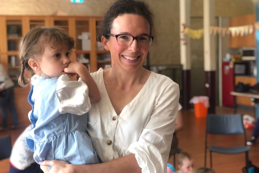 An image of Anne Warren holding her child inside a church room