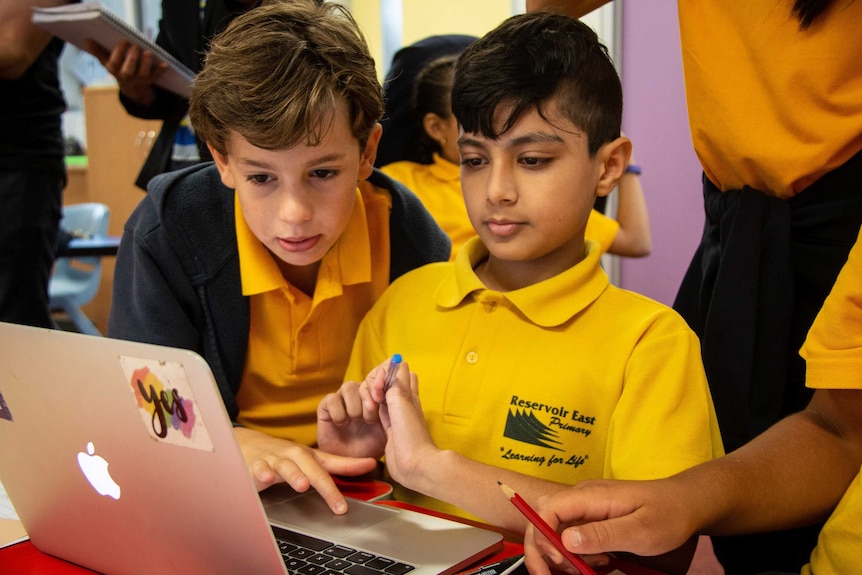 Two young boy students from Reservoir East Primary School learn financial literacy on a laptop.