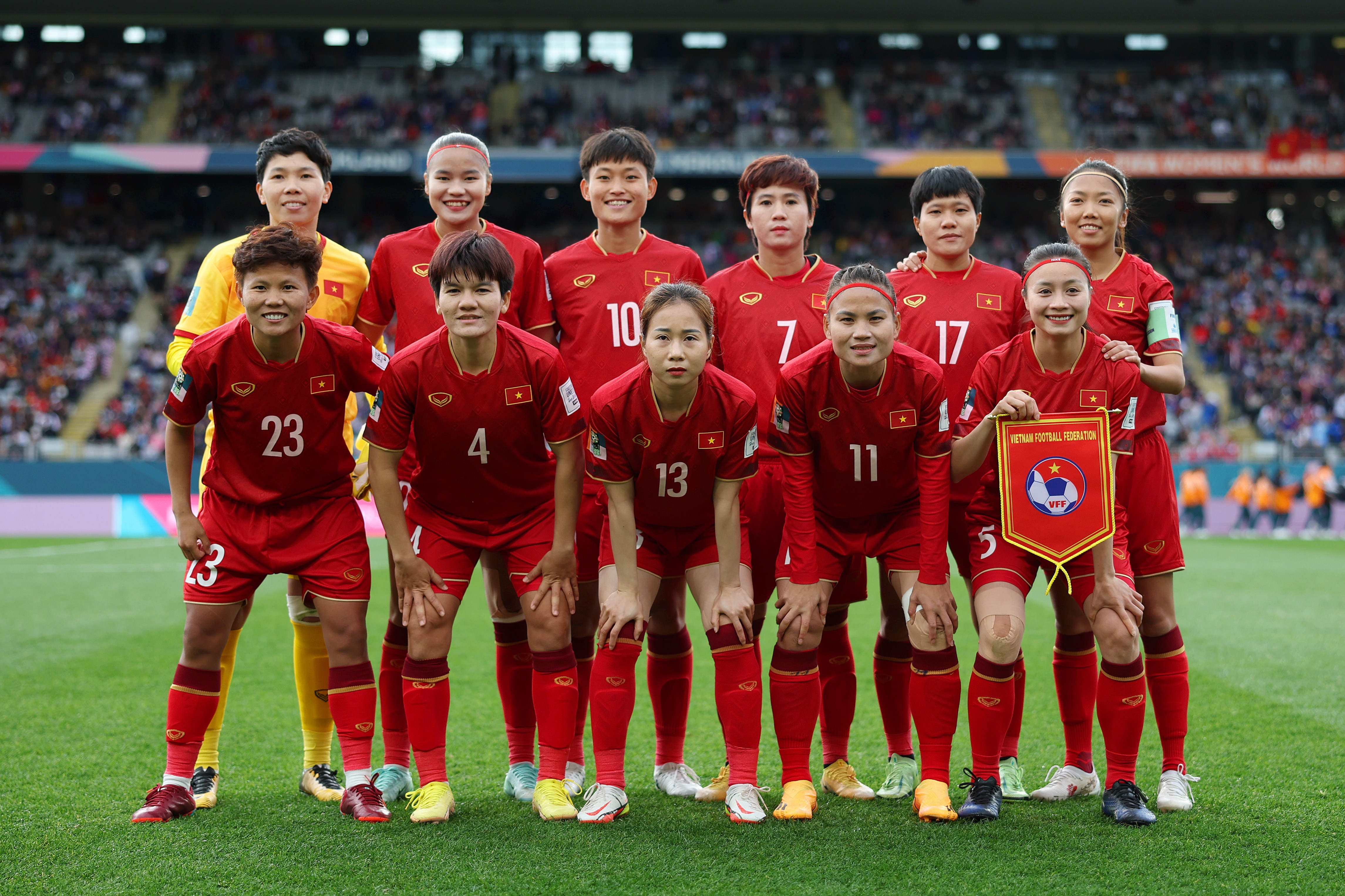 Members of the Vietnam women's football team pose in two rows for a team photo before a game.