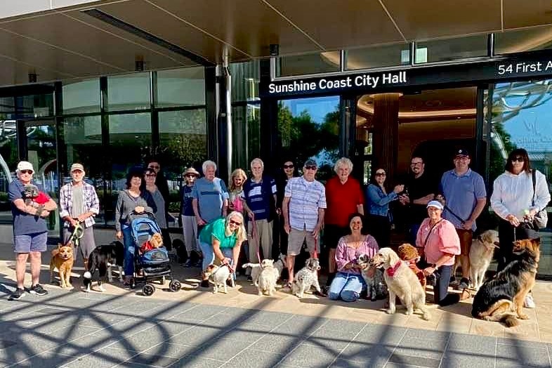 a group of people with their dogs outside a council building
