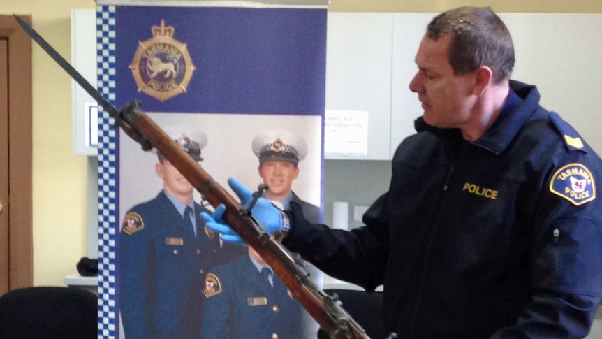 A police officer examines a rifle handed in during the Tasmanian firearm amnesty