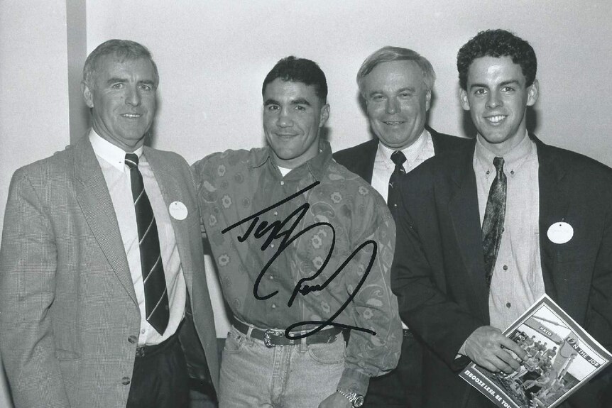 A signed photo showing four, smiling men in formal attire.