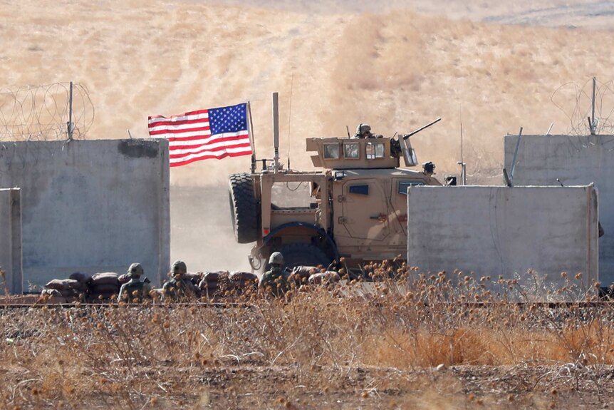 A US flagged armoured vehicle rolling through a desert location