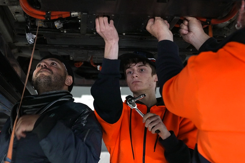 Mr Hemmingsen's apprentices help replace the battery of an EV.