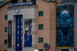 A sign above a stadium says "Chelsea Football Club", with pictures next to it of Chelsea players lifting trophies.